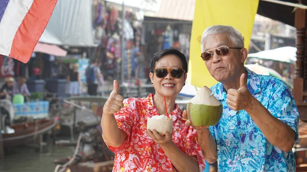Asijské starší pár cestovat do Thajska plovoucí trh. Pití — Stock fotografie