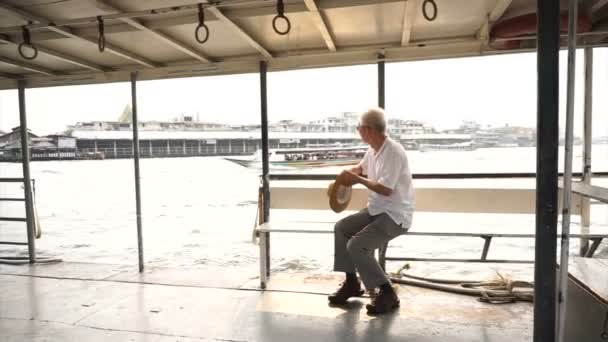 Homme asiatique senior chevauchant un ferry pour traverser la rivière Chaopraya au soleil du matin — Video