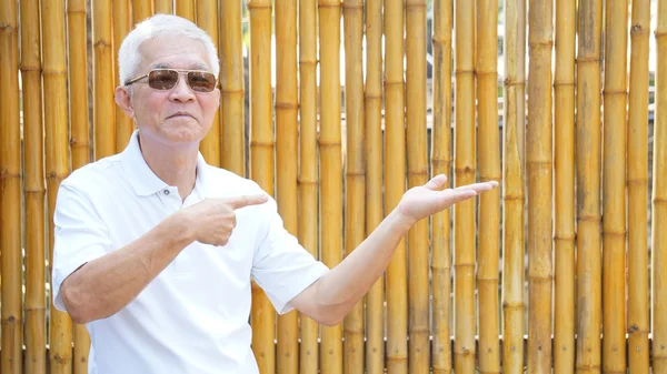 Azjatycki człowiek starszy przedstawić produkt z bambusa złote tło i kopii przestrzeni — Zdjęcie stockowe