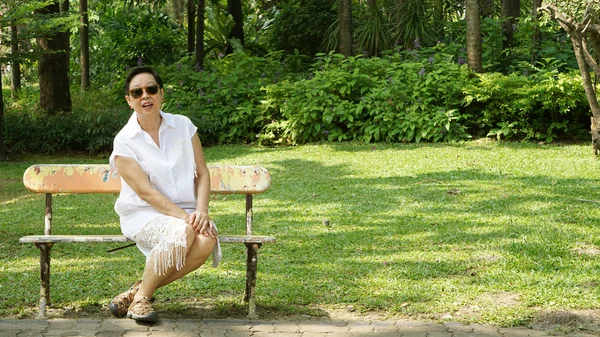 Aziatische senior vrouw zitten alleen in Bank park met kopie ruimte — Stockfoto