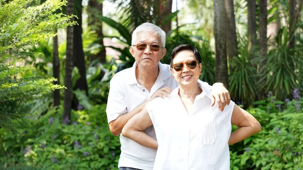 Ázsiai idősebb pár zöld trópusi jellegű háttérrel — Stock Fotó