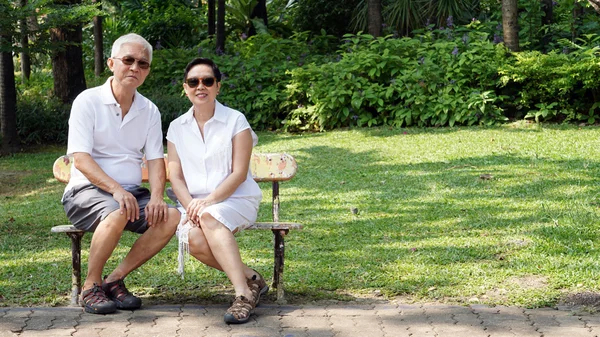 Aziatische senior paar zitten op een bankje in het park met kopie ruimte — Stockfoto