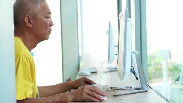 Asiatique senior en utilisant ordinateur de bureau dans un espace intérieur moderne lumineux — Video