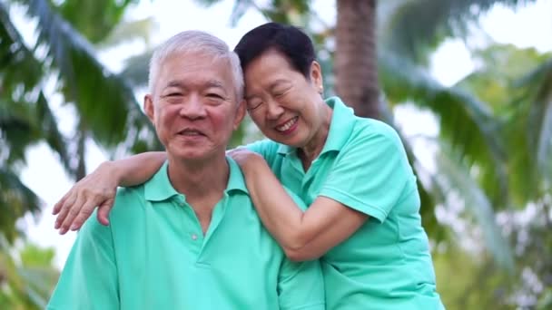 Lyckliga asiatiska senior par promenader motion längs parken. Abstrakt kärlek hälsa och natur — Stockvideo