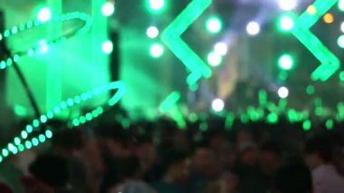 Açık hava konser zevk insan kalabalığı. Renkli yeşil ışık ve su sprey tarafından aydınlatılmış sallama yeşil ışık sopa