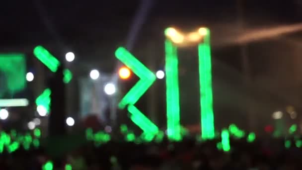 Menschenmenge genießt Open-Air-Konzert. winkenden grünen Lichtstab beleuchtet durch buntes grünes Licht und Wasserspray — Stockvideo