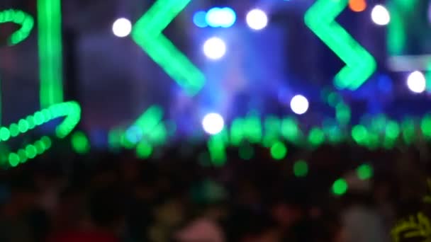 Multitud de personas disfrutando de un concierto al aire libre. Palillo de luz verde ondulante iluminado por luz verde colorida y aerosol de agua — Vídeos de Stock