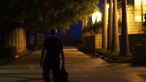 Senior man walking wandering around in the night of city. Wet floor reflects after raining concept of life and loneliness — Stock Video