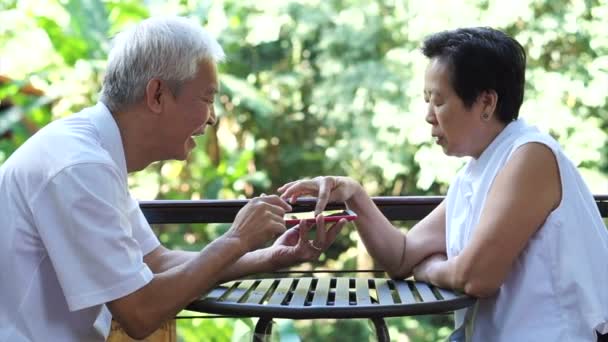 Asiático senior pareja jugando juego juntos en el teléfono inteligente perder divertirse en parque — Vídeos de Stock