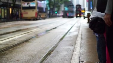 İkonik Hong Kong tramvay taşımacılığı kavramı. Araba yaklaşırken arka plan ile tramvay istasyonunda bekleyen insanlar