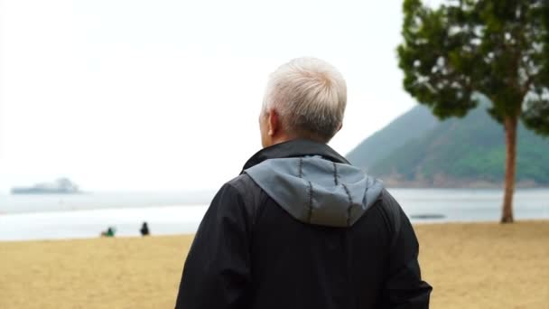 Asiatico senior uomo standing da solo a il spiaggia anteriore — Video Stock