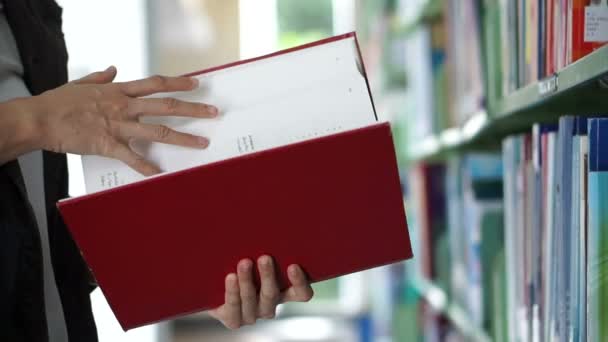 Aziatisch meisje op zoek naar boek, flip door en zet terug op de planken van de bibliotheek — Stockvideo