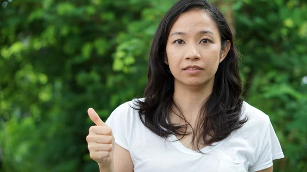 Mixed race Asian girl thumb up surprised nature background — Stock Photo, Image