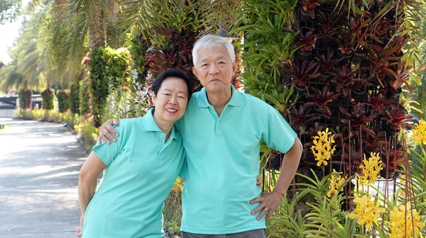 Старшая азиатская пара улыбается вместе на зеленом фоне природы — стоковое фото
