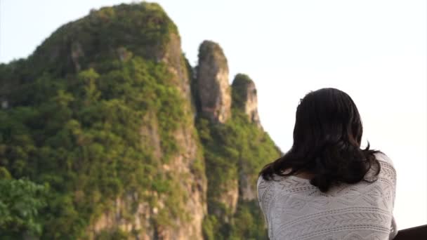 Chica asiática de pie y mirando fijamente al sol puesta por la montaña de piedra caliza — Vídeos de Stock