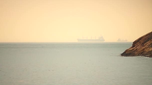 Cargo freighter ship sailing, moving at ocean horizon golden sky in hazy sea — Stock Video