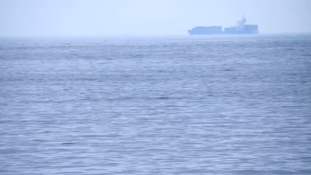 Cargo freighter ship sailing, moving at ocean horizon sky in hazy sea — Stock Video