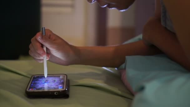 Femme couchée sur le lit et jouant à des jeux sur téléphone intelligent la nuit — Video