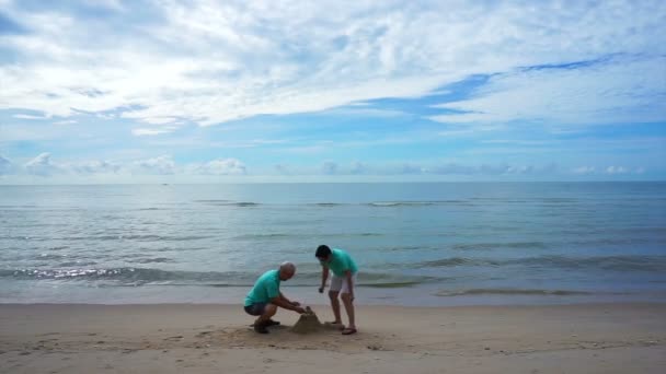 Азиатская старшая пара, украшающая песчаный замок на пляже. Абстрактный вклад в жизнь — стоковое видео