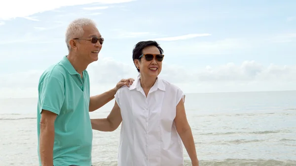 Asian senior couple walking together on beach by the sea — Stock Photo, Image