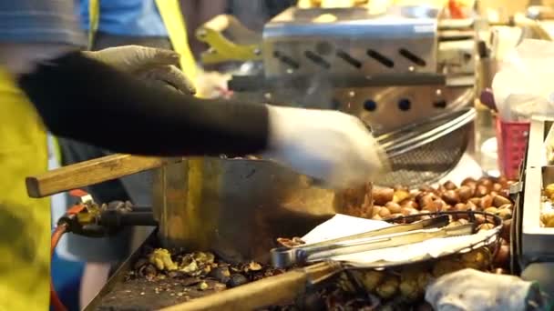 Vendedor grelhando lulas e descascando castanha assada na banca de comida de rua. Comida de outono de Ásia — Vídeo de Stock