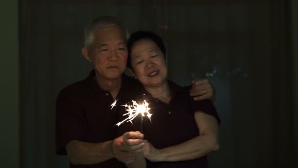 Азиатская старшая пара играет в фейерверки, искры, огненные крекеры ночью. Концепция празднования жизни — стоковое видео
