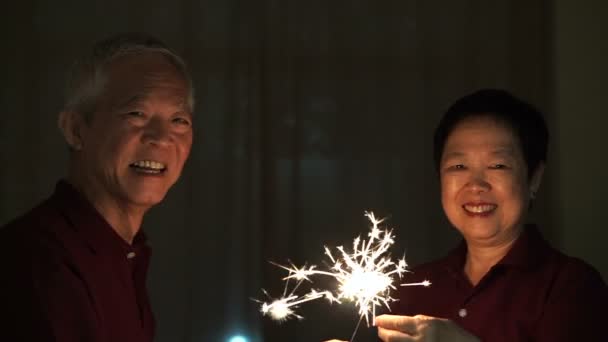 Casal sênior asiático jogando fogos de artifício, faíscas, fogo de artifício à noite. Conceito celebrando a vida — Vídeo de Stock