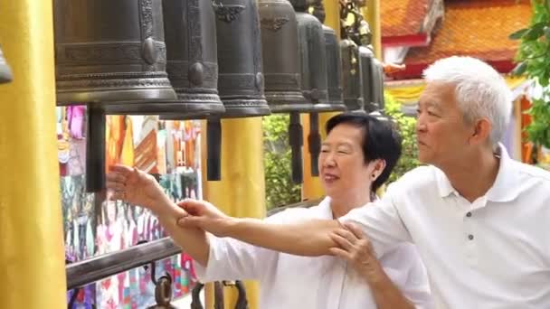 Asijské starší pár rituální zvonění v buddhistickém chrámu věří, pro štěstí — Stock video