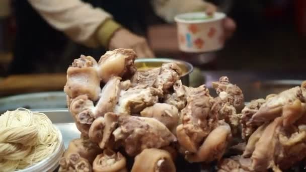 Chinese noodle with pig leg on top at night market stall — Stock Video