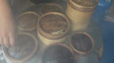 Şefin elleri Çin restoranında buharlı tencere sepetlerinin etrafında dolanıyor.