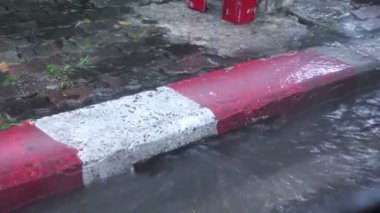 Yağmur mevsiminde yol kenarındaki oluktan akan su.