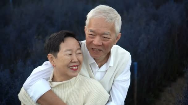 冬の花畑で引退を祝うアジアの幸せなシニアカップル 青魔法の背景 — ストック動画