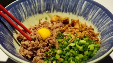 Çubuklar kurutulmuş erişte, yeşil soğan ve yumurta sarısı karışımı Çin eriştesi yiyor.