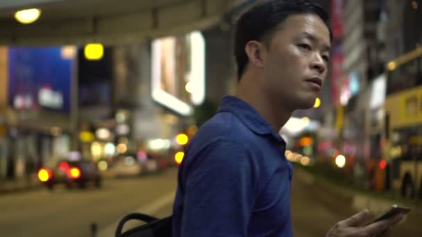 Ázsiai Fiatalember Várja Buszmegálló Használata Közben Okostelefon — Stock videók