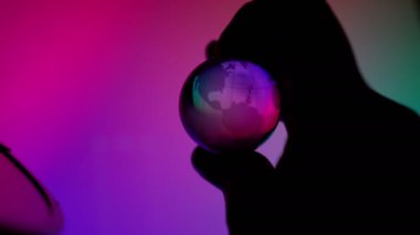 Finger holding transparent neon light globe ball control technonogy to help or destroy planet
