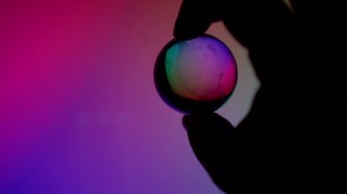 Hand holding transparent neon light globe ball control technonogy to help or destroy planet