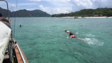 Tourist activity snorkeling in Phuket island bay next to private long tail boat