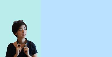 Havalı kısa saçlı Asyalı genç yetişkin kadın yaşam tarzı kulaklık fotokopi alanı ile düşünen güneş gözlüğü.