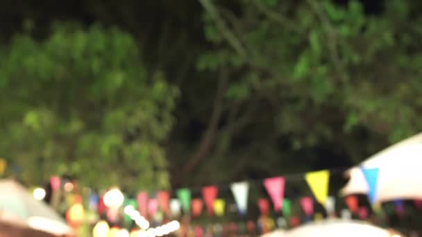 Festival traditionnel asiatique dans le jardin les gens marchent acheter des achats et manger avec des lumières et des drapeaux la nuit — Video