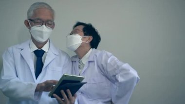 Asyalı yaşlı doktorlar hastane kişisel bilgilerini özelleştirmek için tablet kullanıyorlar.