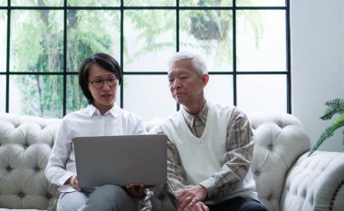 Dizüstü bilgisayarla veri gösteren üst düzey Asya danışmanı yatırım ve sağlık hizmetleri hakkında tartışır