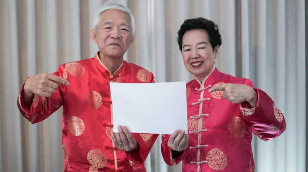 中国の新年の衣装のシニアカップルは コピースペースプロモーションのためのサインを保持します — ストック写真