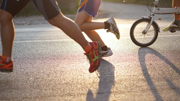 Andar de bicicleta e correr ao sol da manhã — Fotografia de Stock