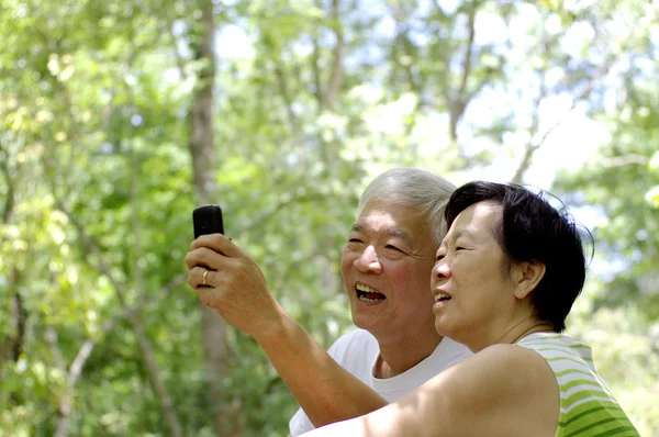 Asian senior couple using cell phone — Stock Photo, Image