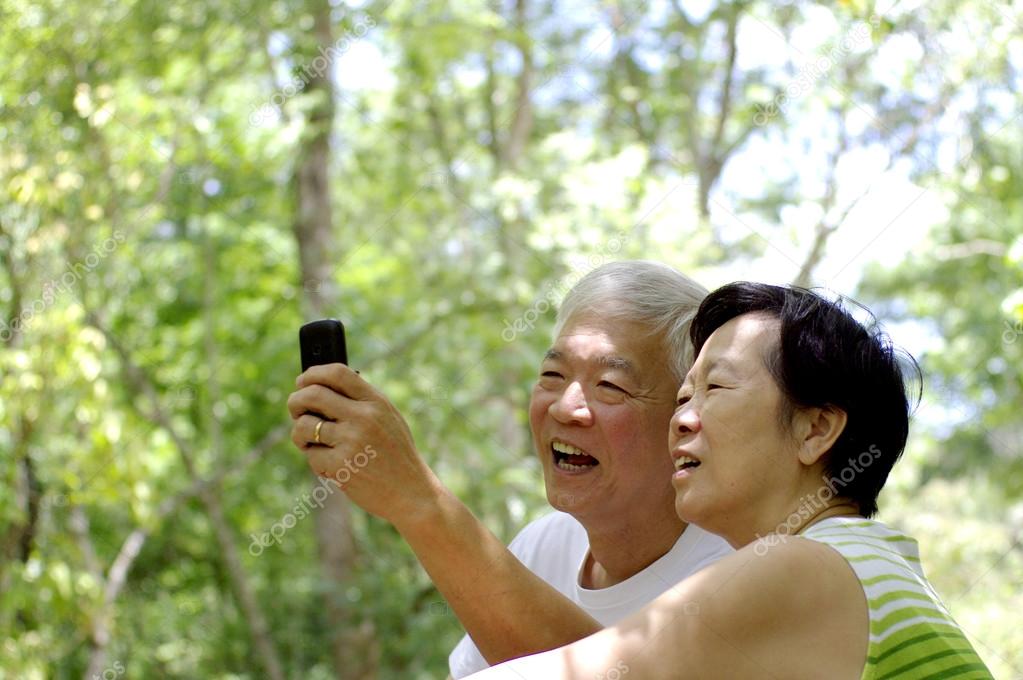 Asian senior couple using cell phone