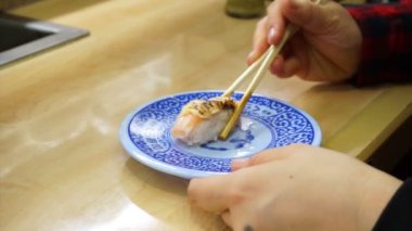 Asyalı kız somon nigiri bir konveyör kayışı suşi restoranında yemek