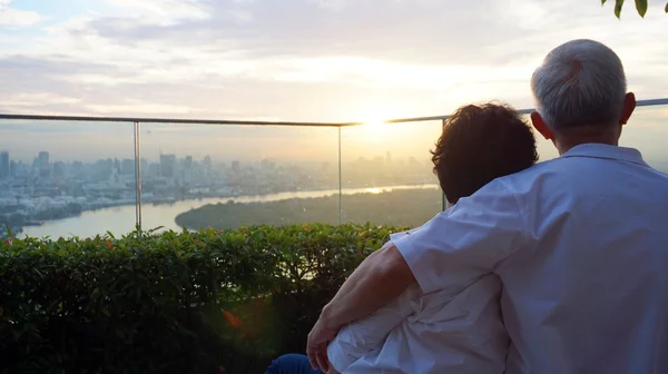 Senior looking at sunrise together over city skyline — Stock Photo, Image