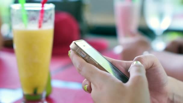 Vídeo de mão jogando telefone inteligente em feriado tropical. fundo de smoothies de frutas e óculos de sol — Vídeo de Stock