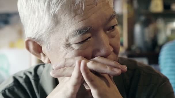 Asian senior guy with hand on face and thinking — Stock Video