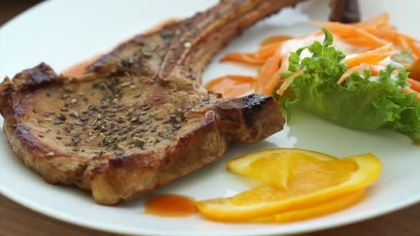 Bife de peixe batido e bife de porco grelhado com osso. salada colorida e vegetal — Vídeo de Stock